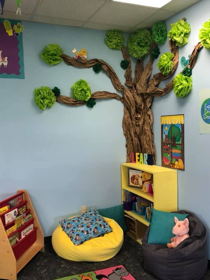 Classroom reading nook with a tree mural, beanbag chairs, and bookshelves