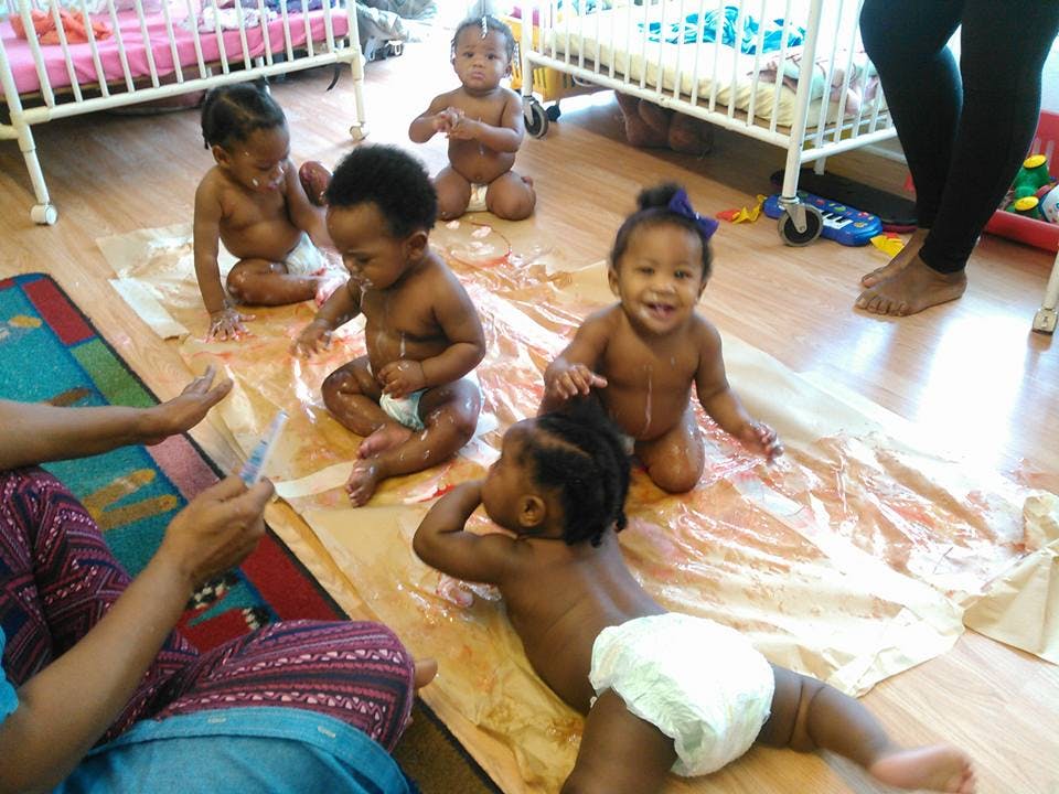 Multiple babies on a mat with a person sitting nearby