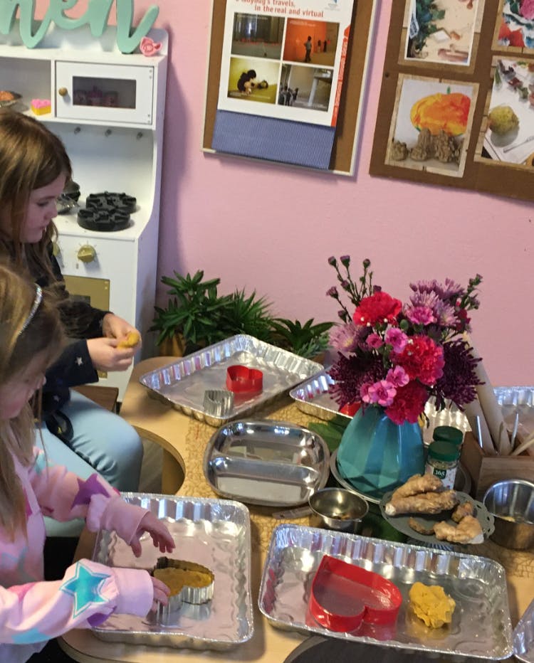 Two children playing with cookie cutters and dough on trays