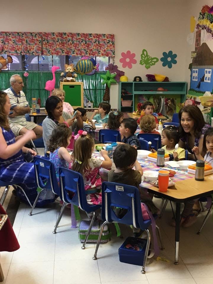 Adults and children sitting at tables in a classroom