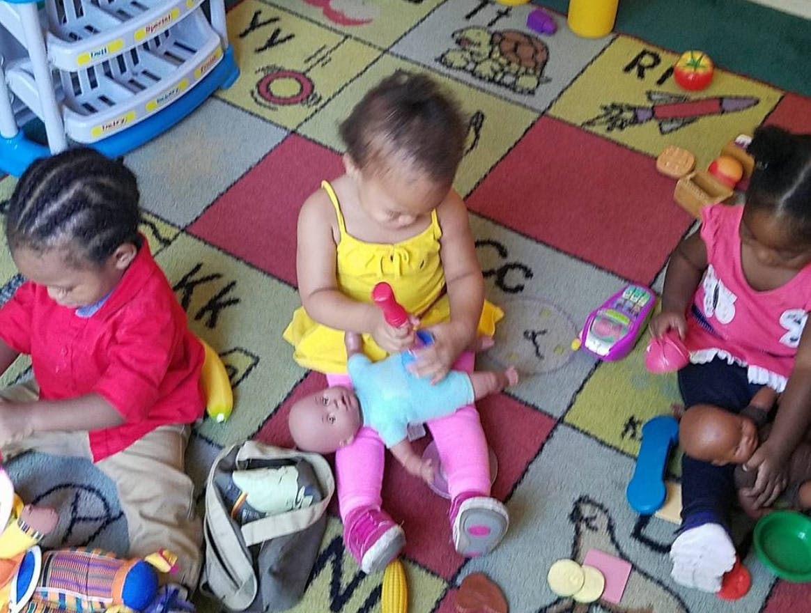 Three children playing with toys on a colorful rug