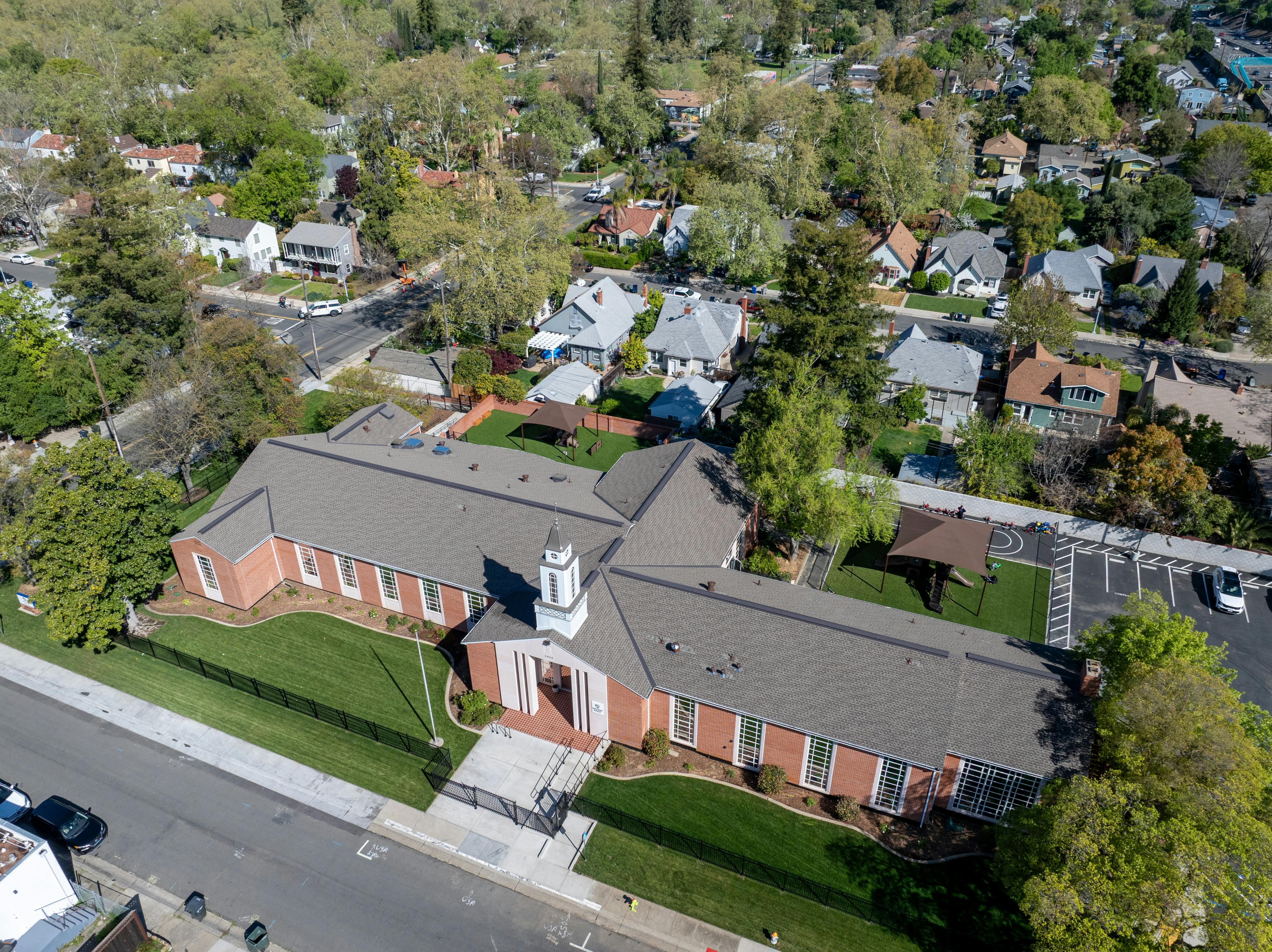 Aerial view of a brick building with a gray roof and steeple