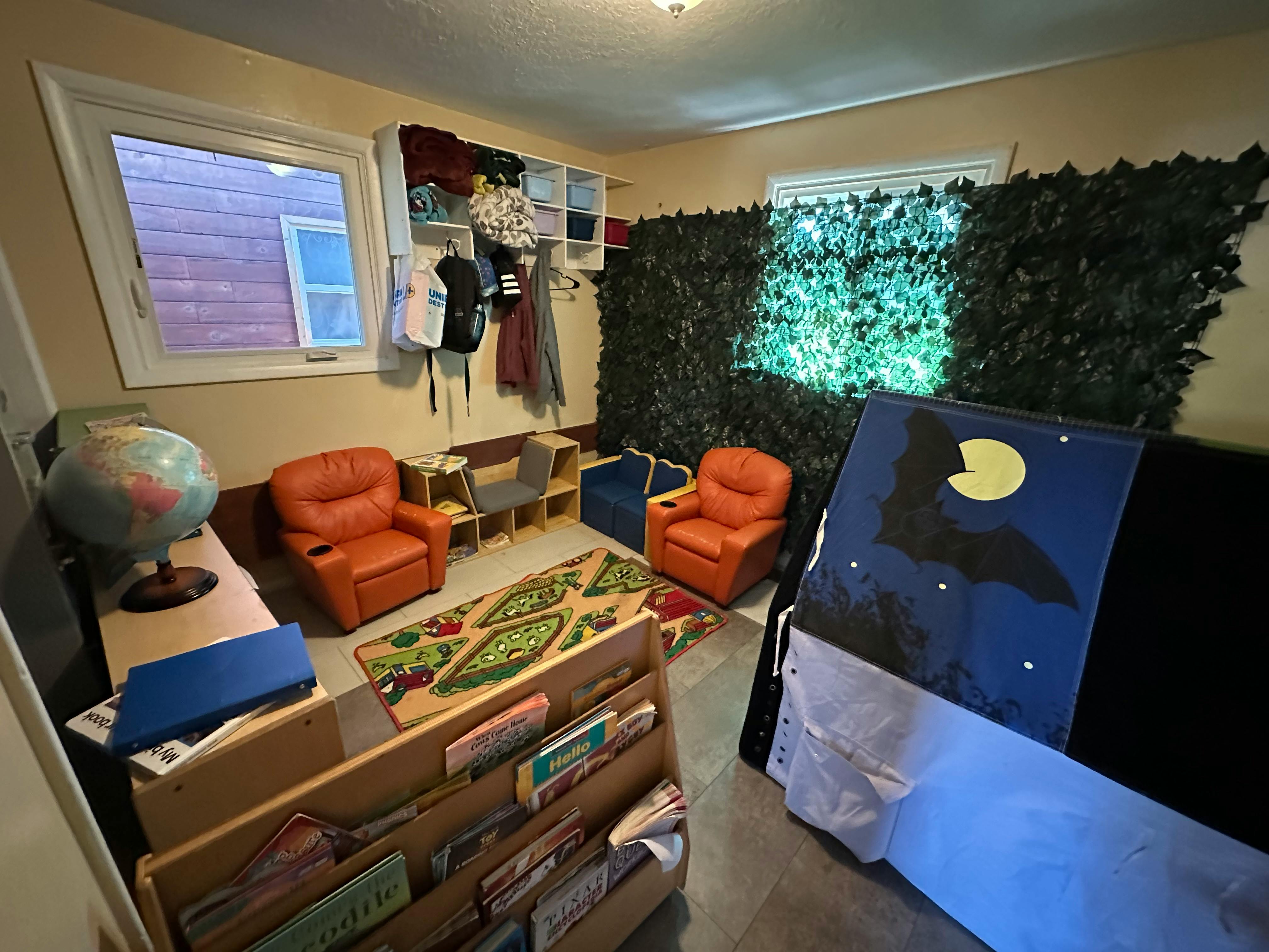 Children's play area with small chairs, rug, and a tent with a bat design
