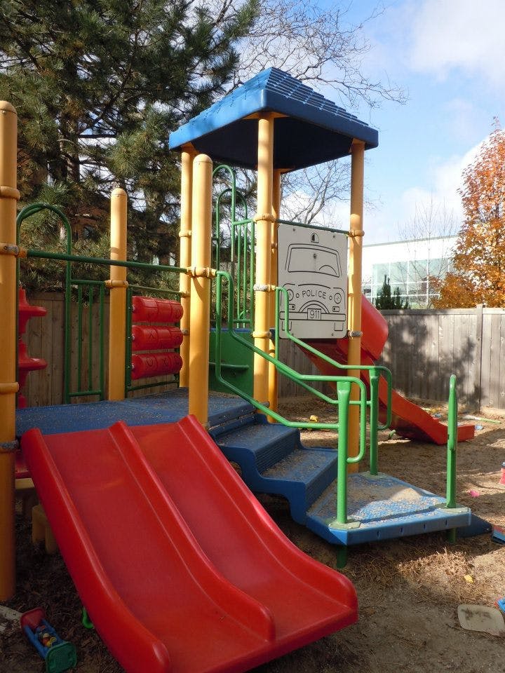 Playground structure with red slides, blue stairs, and yellow poles
