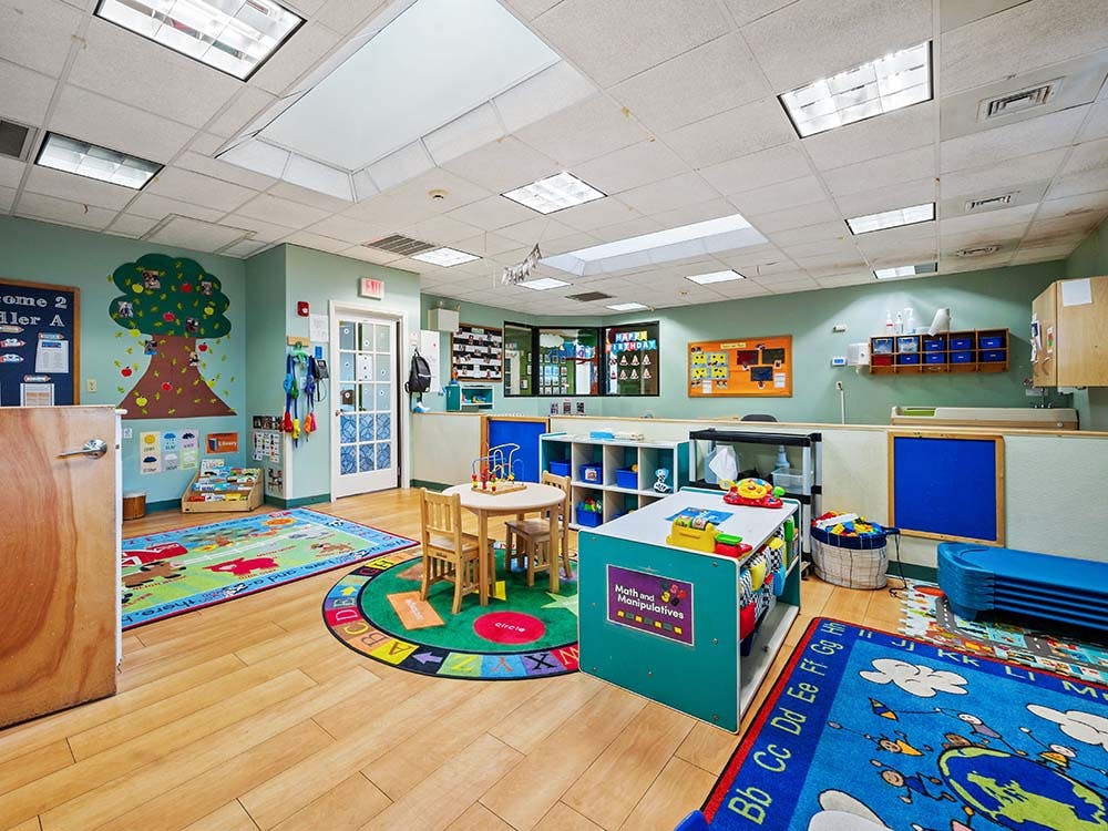 Colorful preschool classroom with activity areas and small furniture