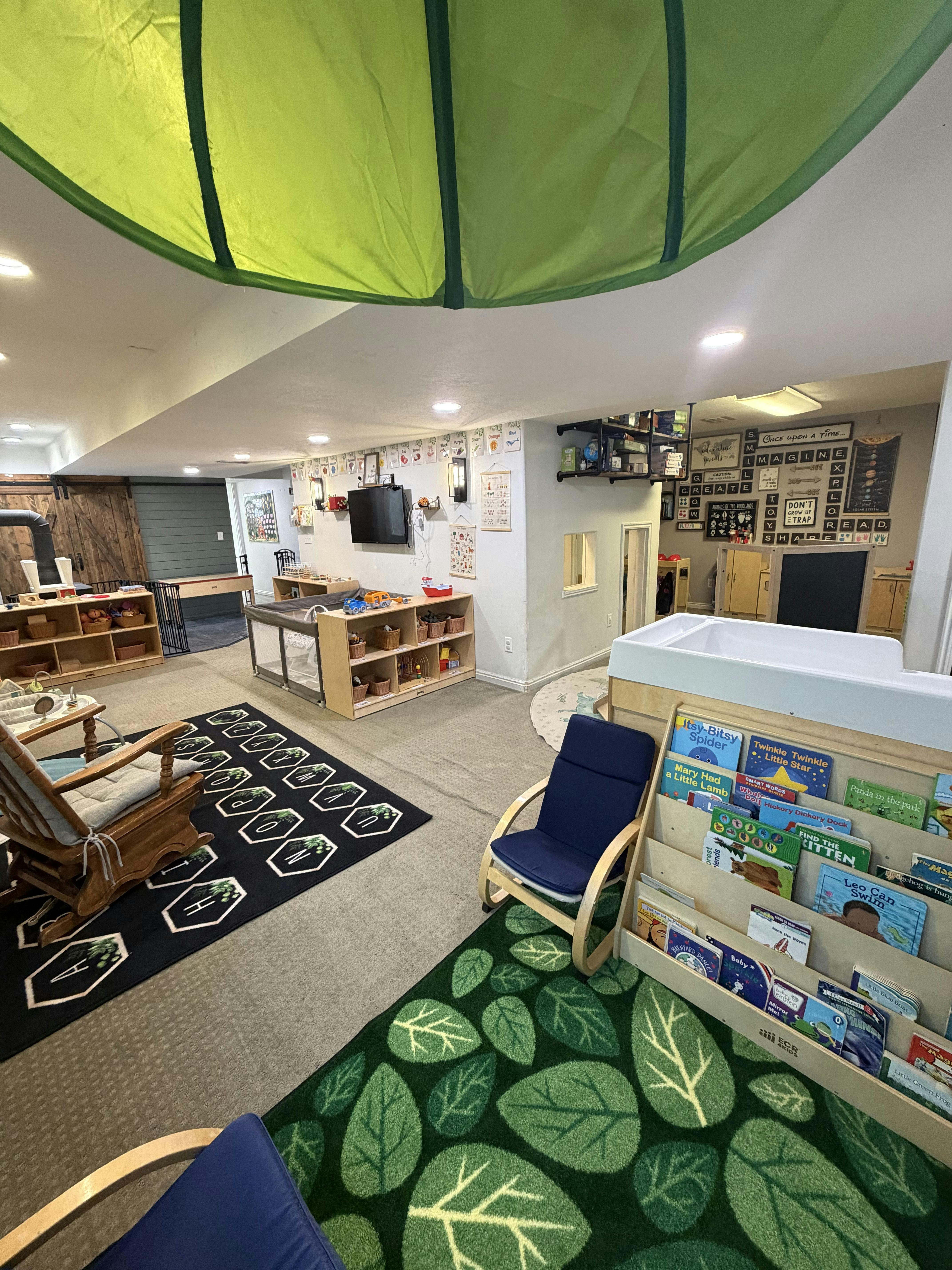 Brightly lit childcare playroom with bookshelves, play areas, and educational decor