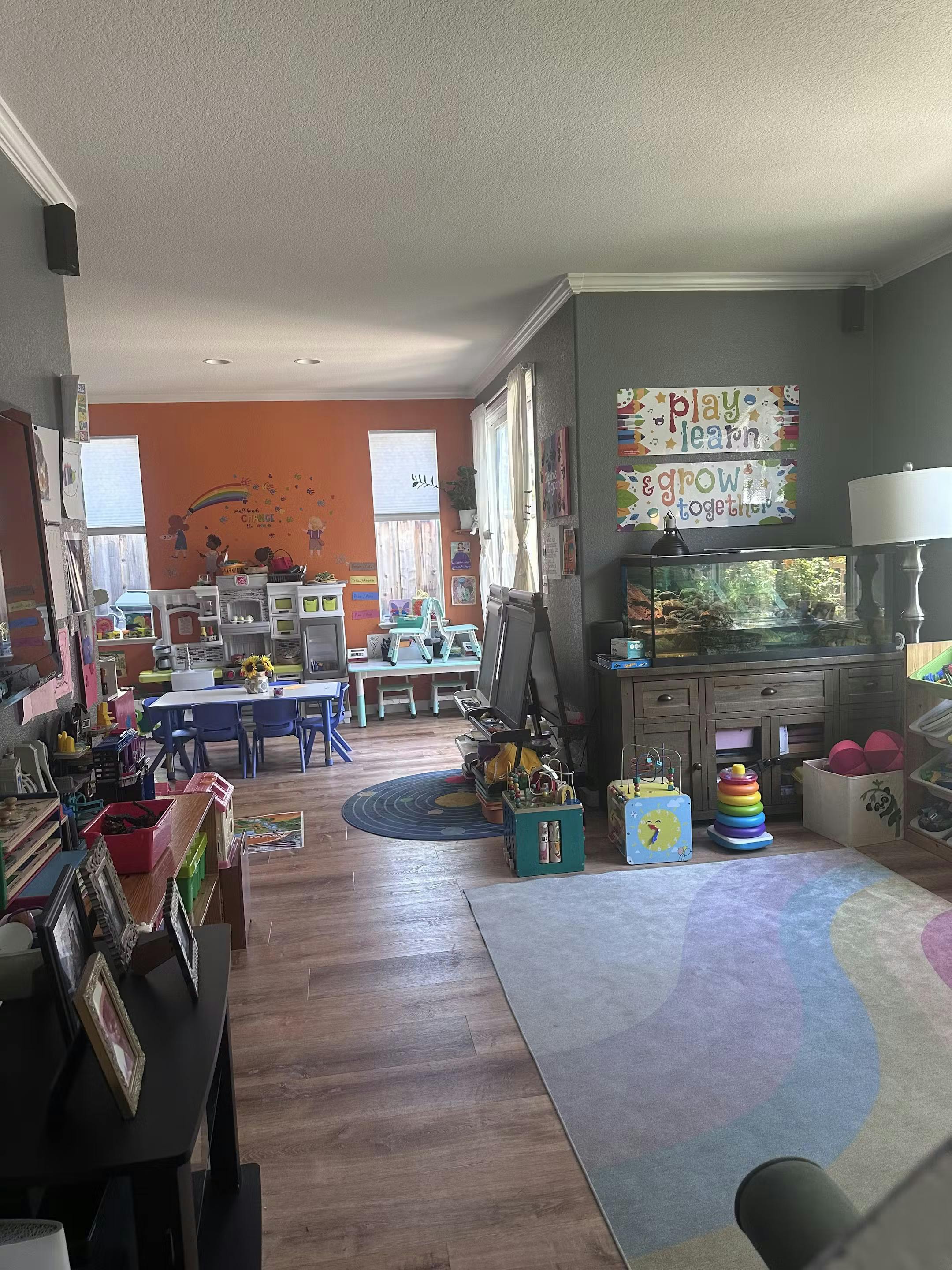 A room with tables and chairs, toys, and a rug with a colorful design