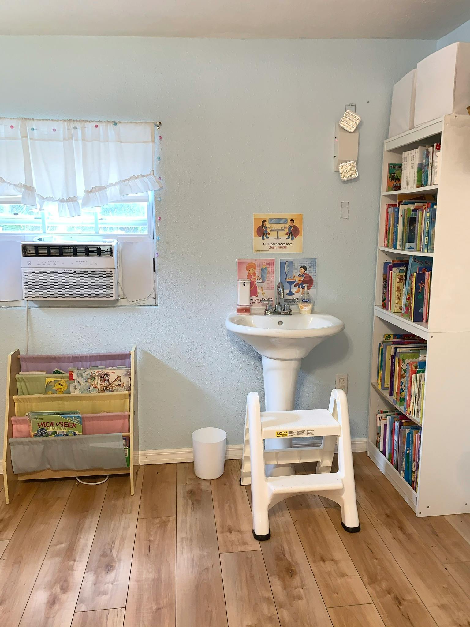Classroom with a sink, step stool, book display, and bookshelf