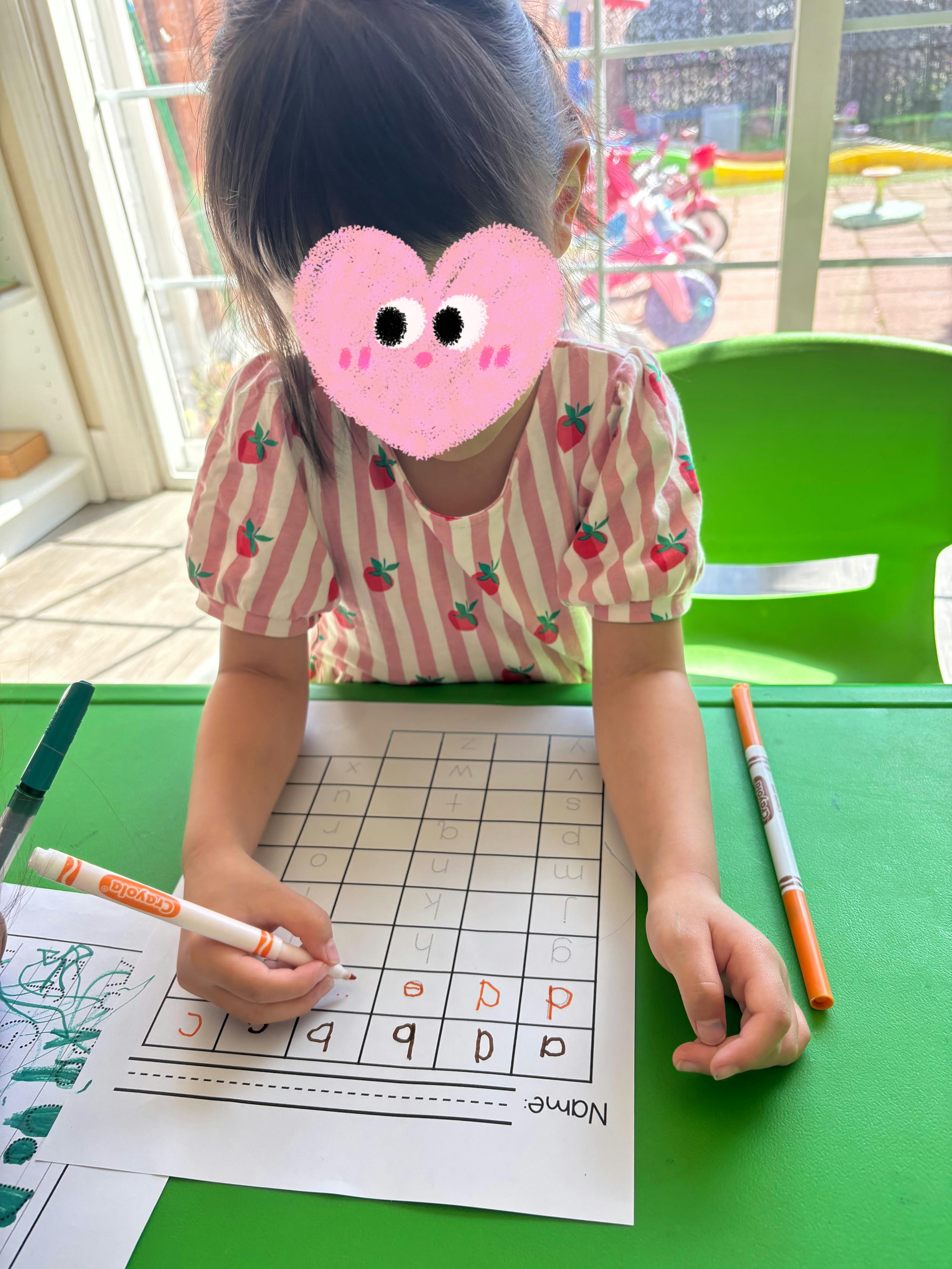 Child practicing lowercase letter writing on a worksheet at a table