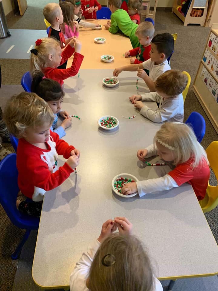 Children sitting at tables doing an activity with small beads