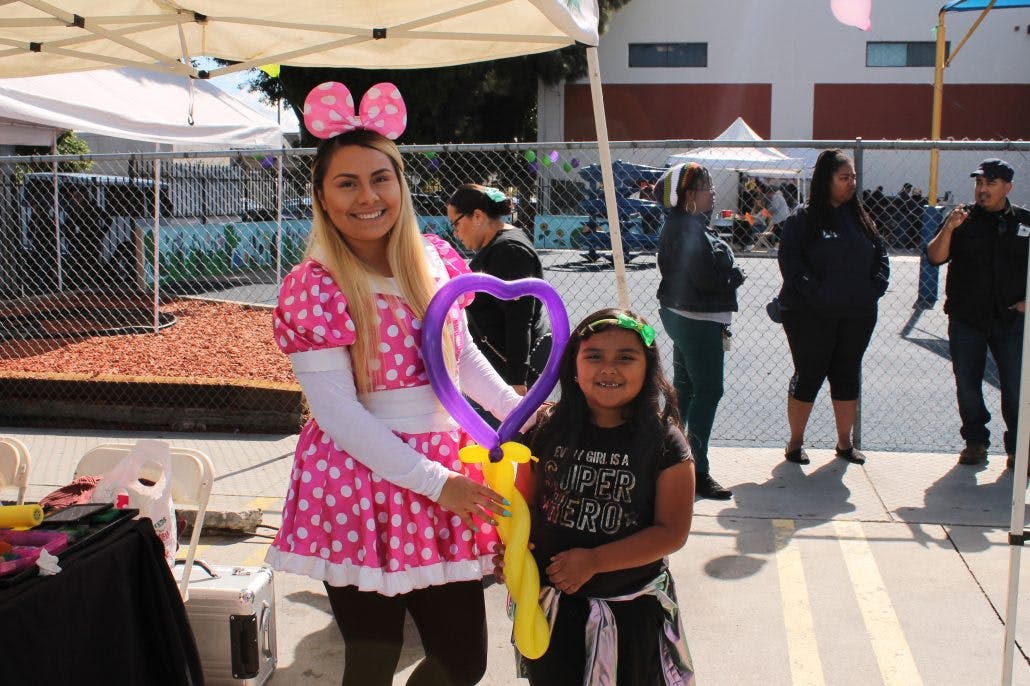 Person in polka dot dress and child holding balloon