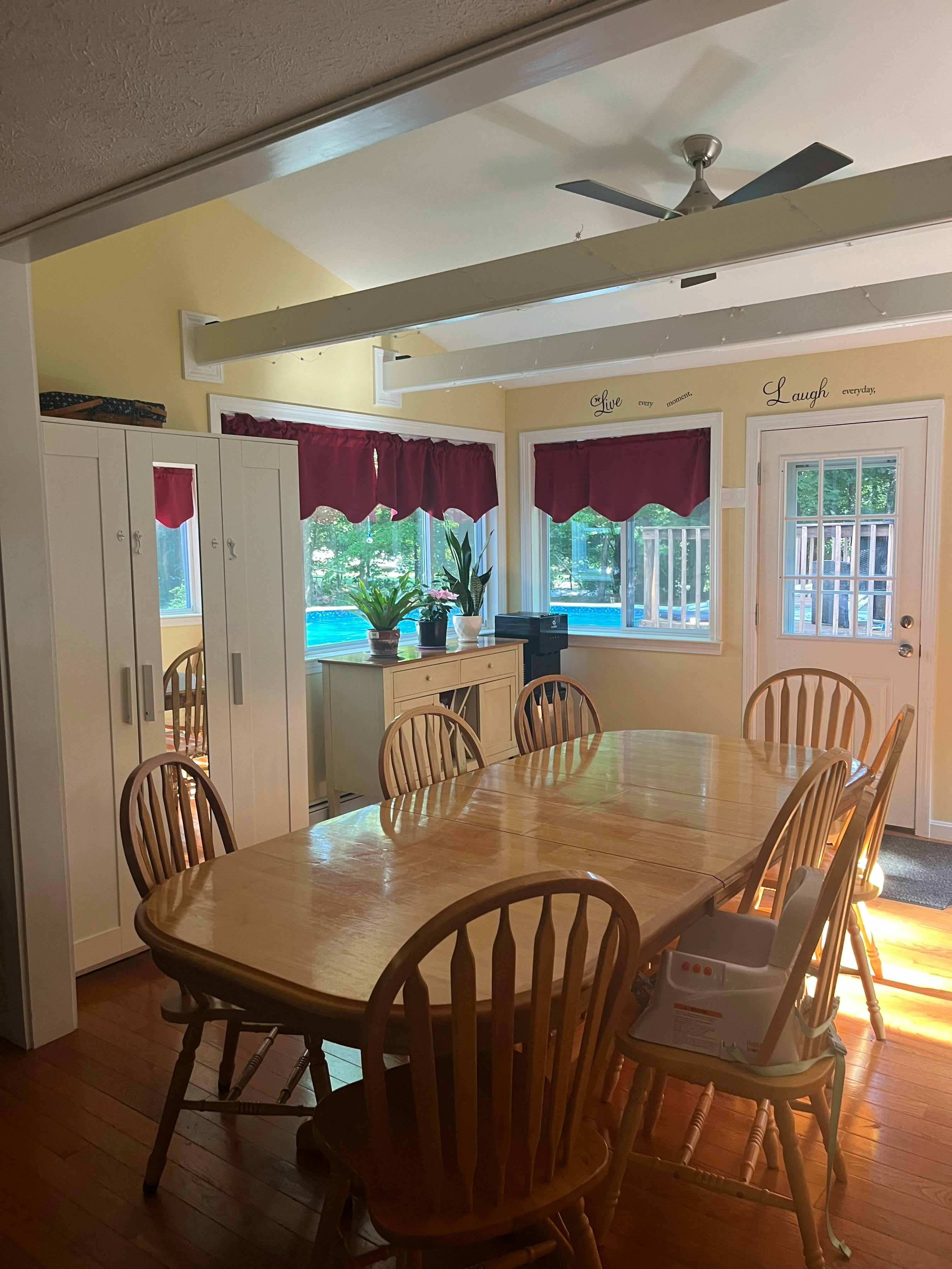 Dining room with a wooden table and chairs, windows with red valances
