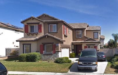 Two-story house with red shutters and two vehicles in the driveway