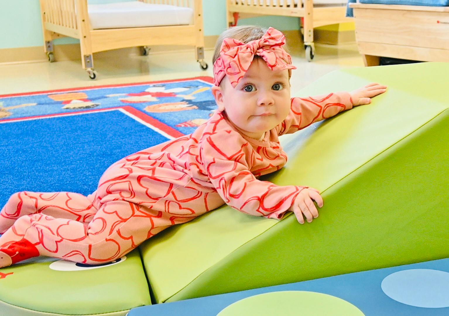 Child lying on a soft play wedge in a classroom