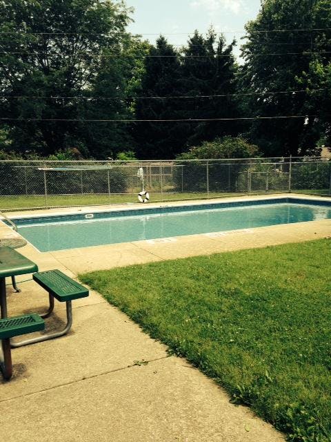 Empty outdoor swimming pool with a green picnic table next to it
