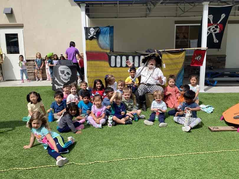 Group of children seated on grass around a person in a pirate costume