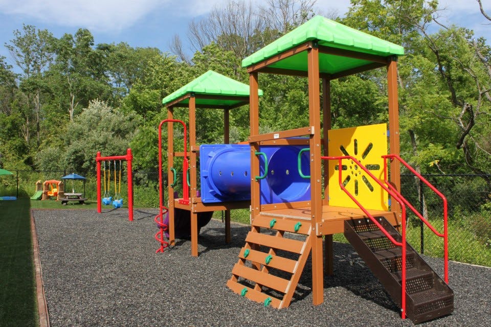 Playground with a wooden structure, blue tunnel, and red swings