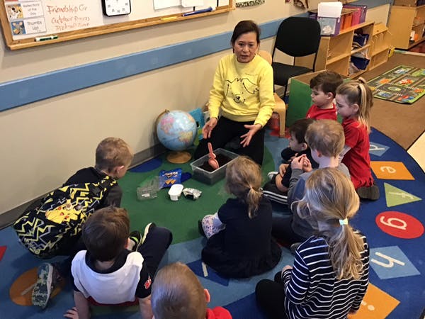 Adult and children sitting on a rug in a classroom