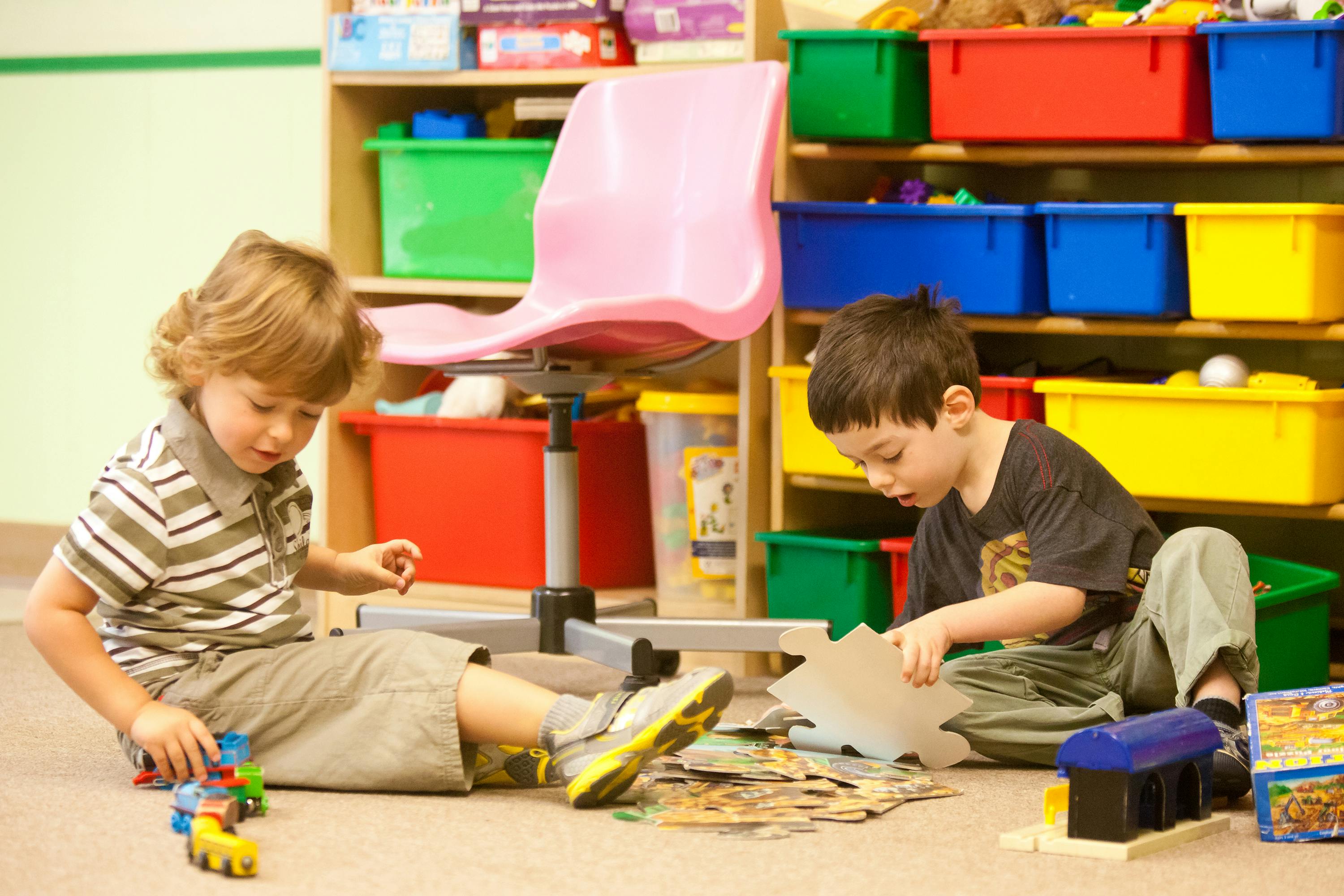 Two children playing on the floor in a classroom