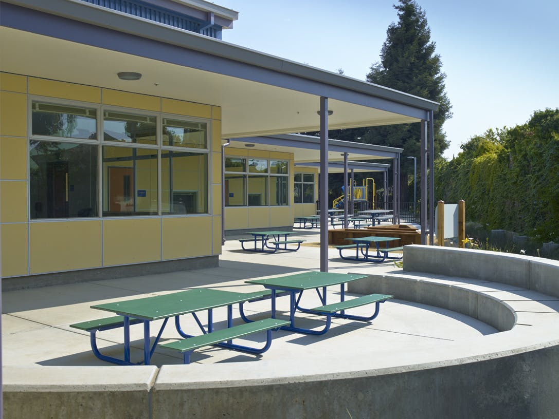 Outdoor eating area with green picnic tables and benches