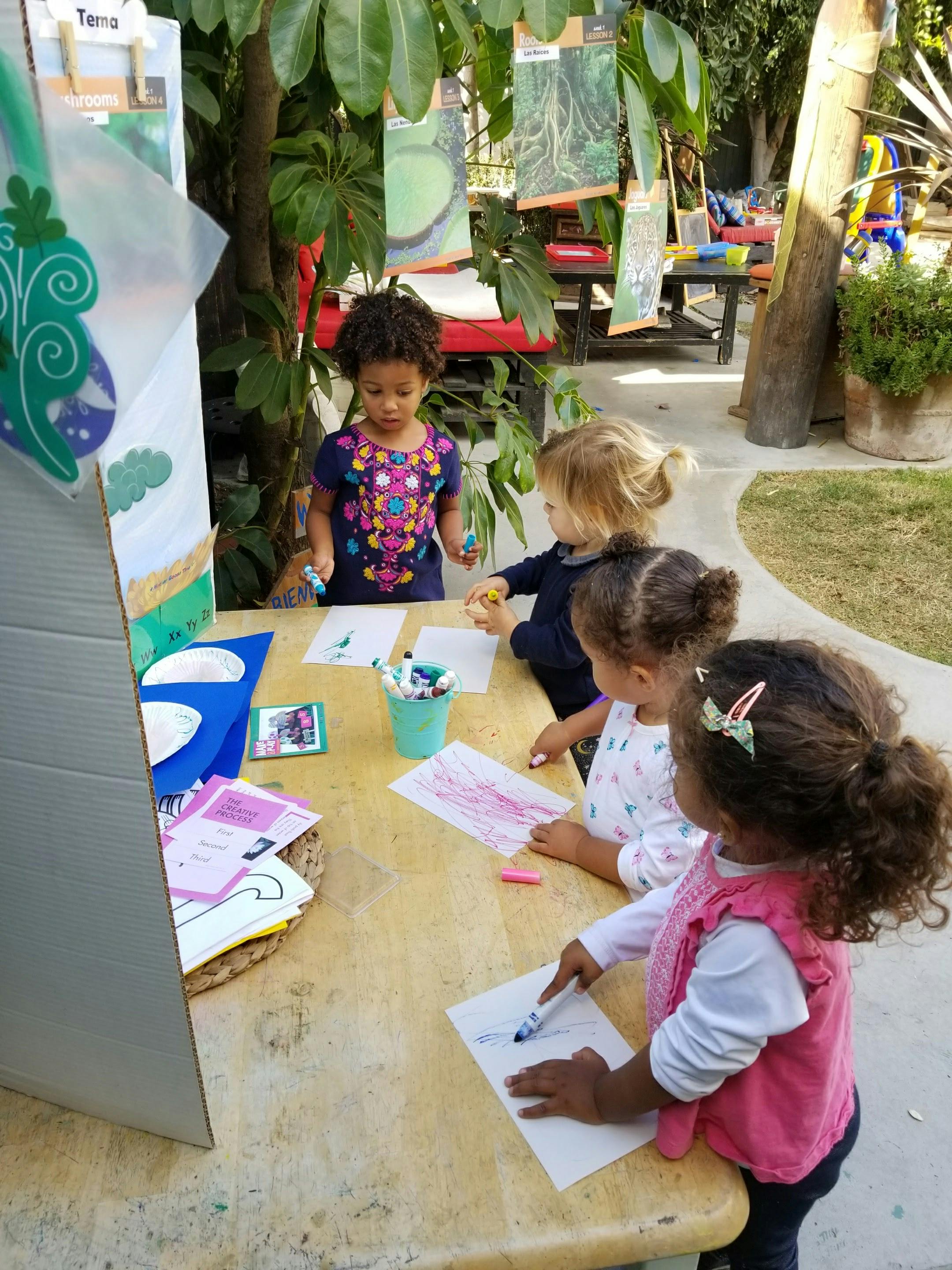 Children drawing at a table outdoors