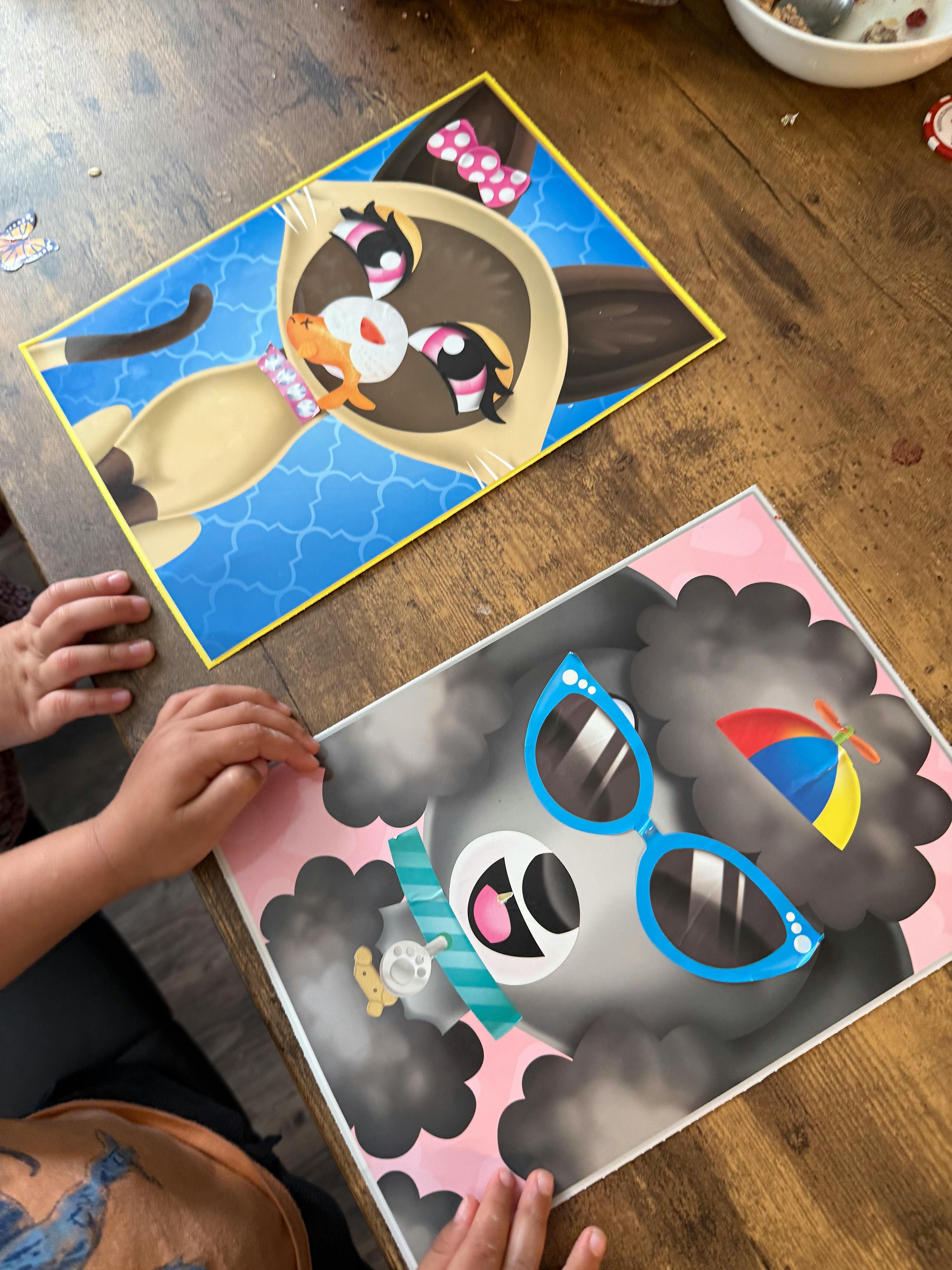 Child's hands next to two cartoon animal cutouts on a wooden table