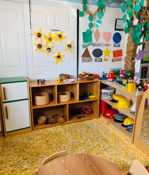 Classroom with shelves of toys and learning materials, yellow rug