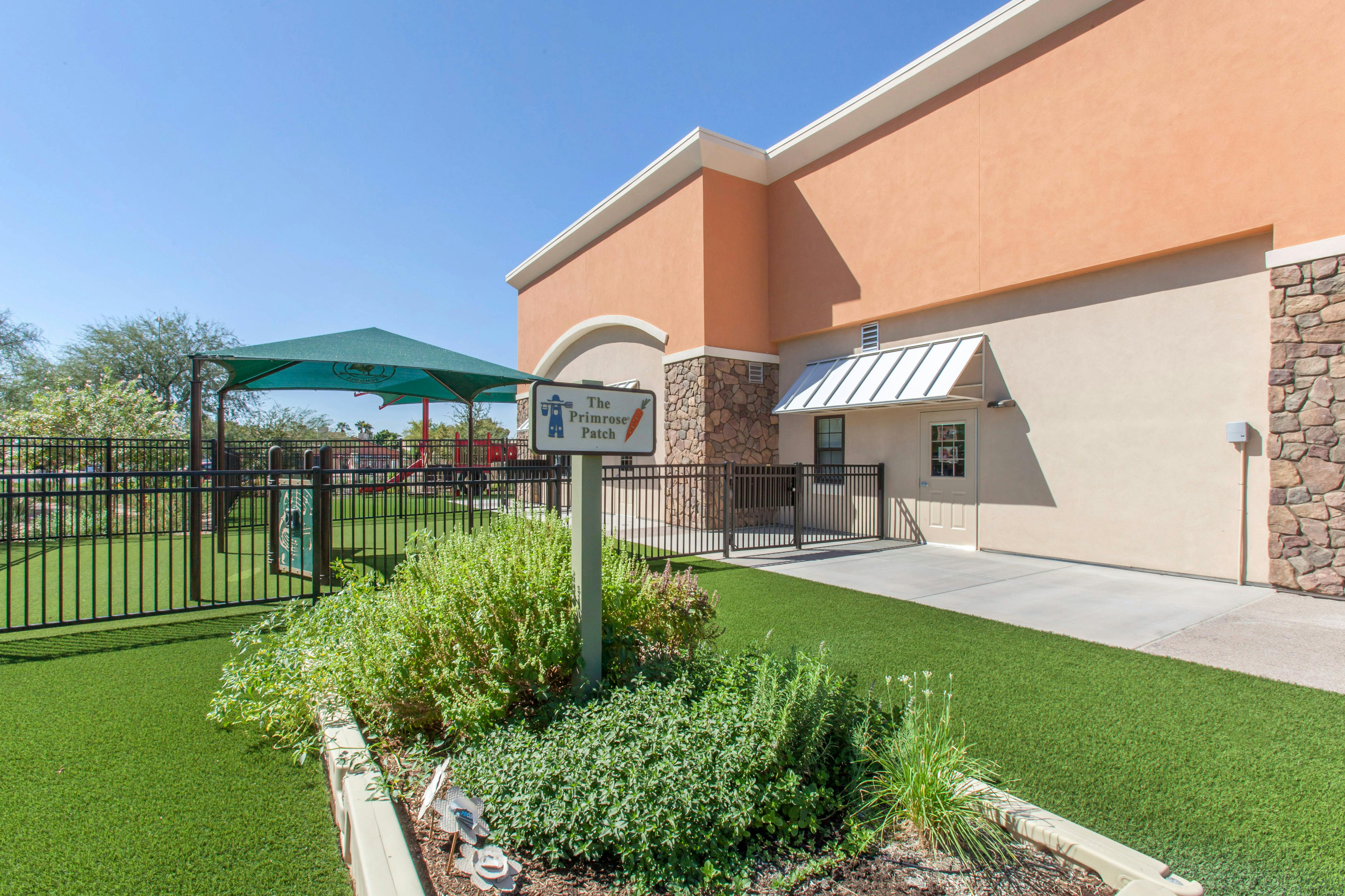 A tan building with a playground and a sign reading "The Primrose Patch"