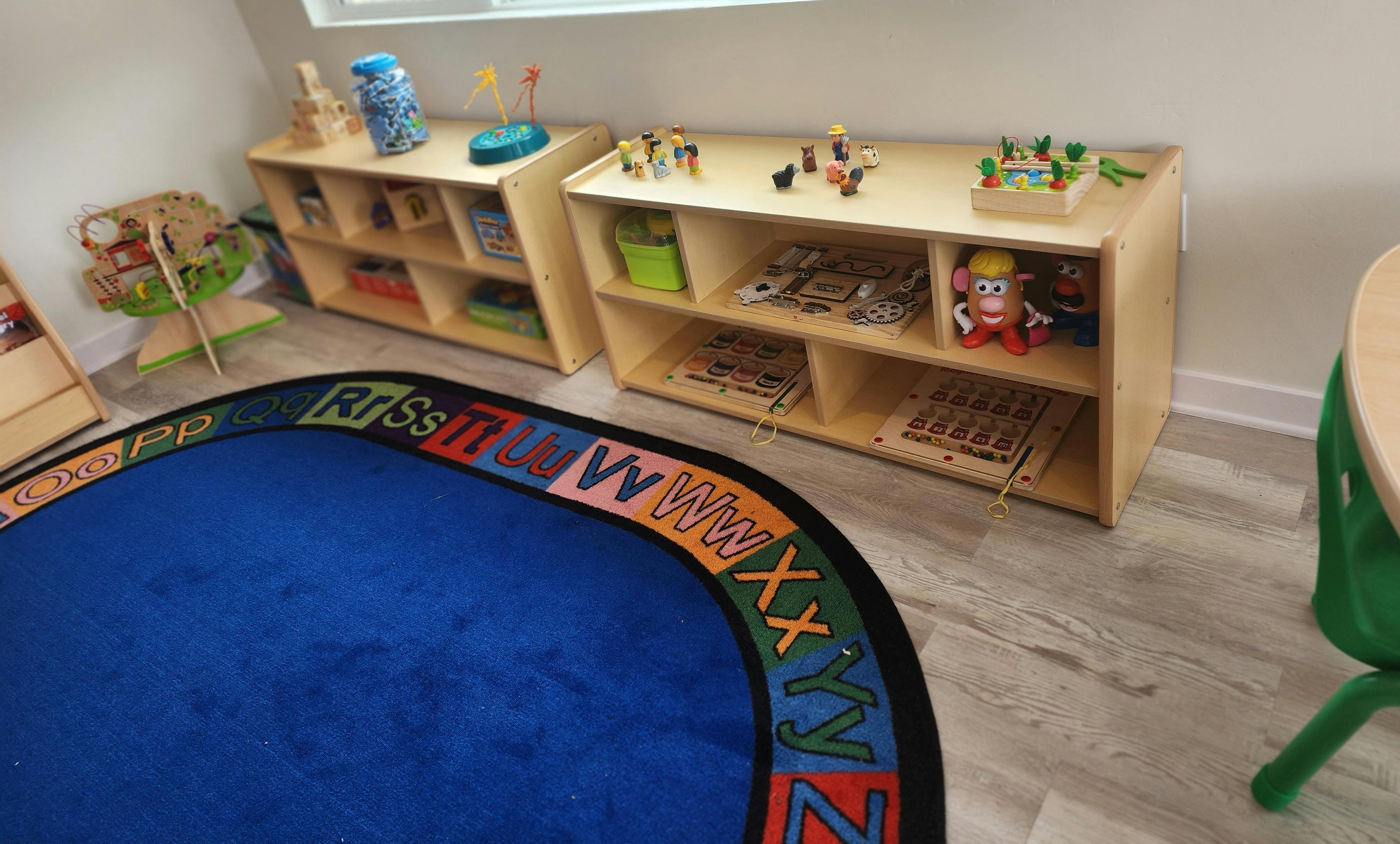Classroom with alphabet rug and shelves of toys