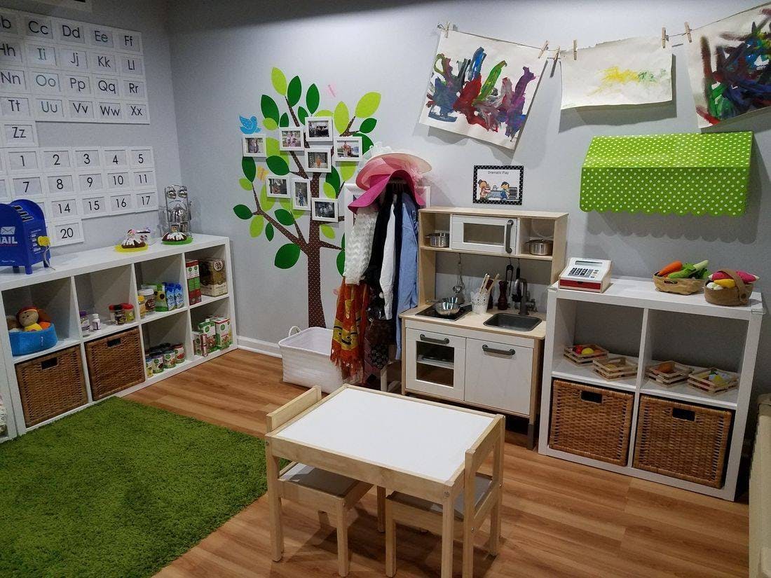 Playroom with small table and chairs, toy kitchen, and shelves with shelves with baskets