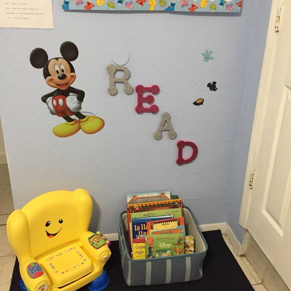 Mickey Mouse wall decal, "READ" letters, yellow toy chair, and books in a bin