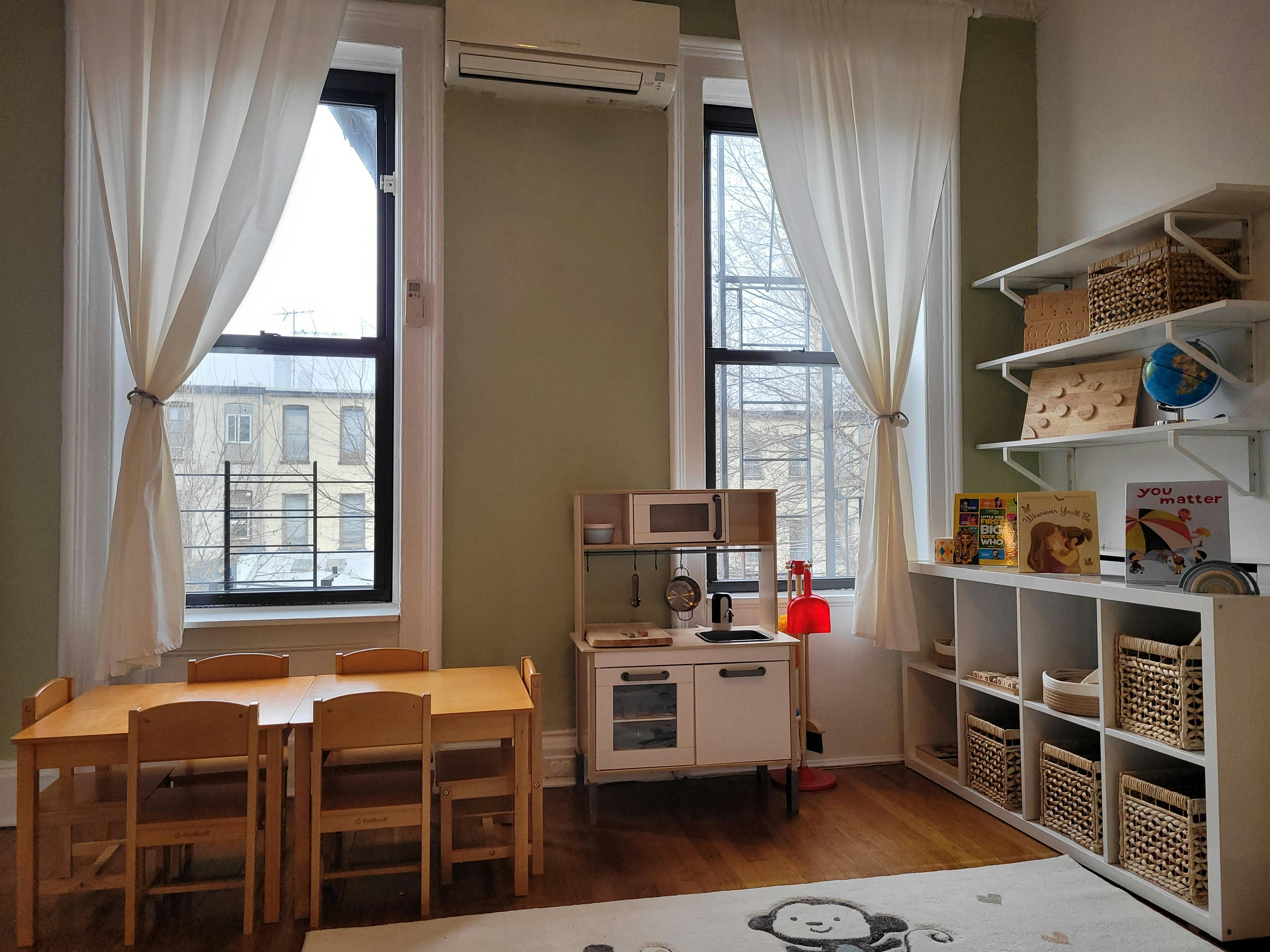 Playroom with small table and chairs, toy kitchen, and shelves with baskets