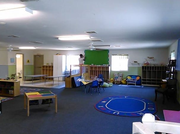 Classroom with blue carpet and various furniture, person standing on a ladder