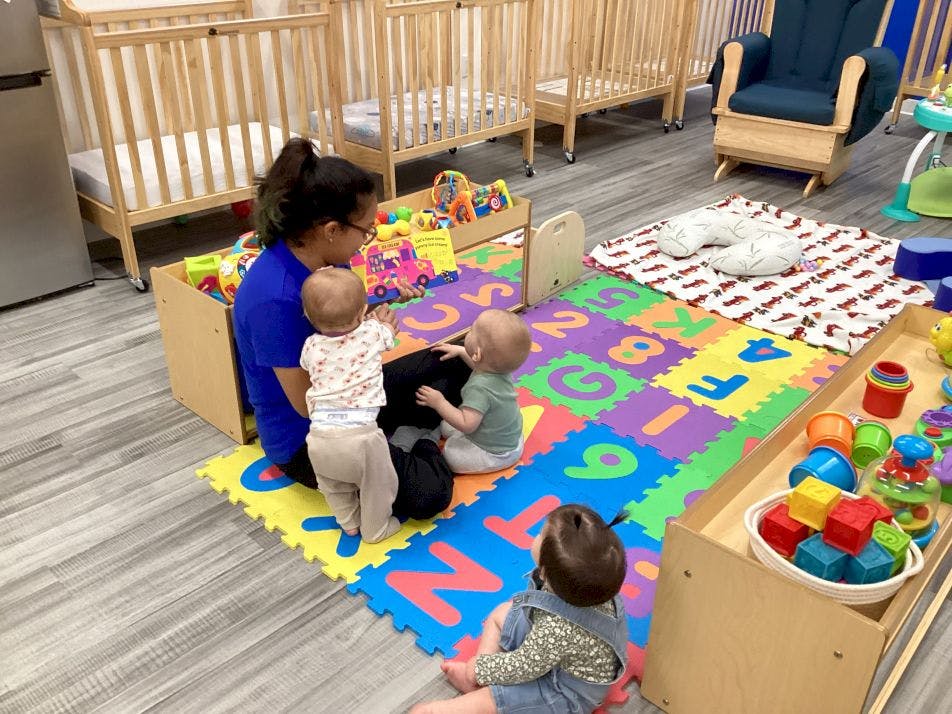 Person sitting on floor with three children in a play area