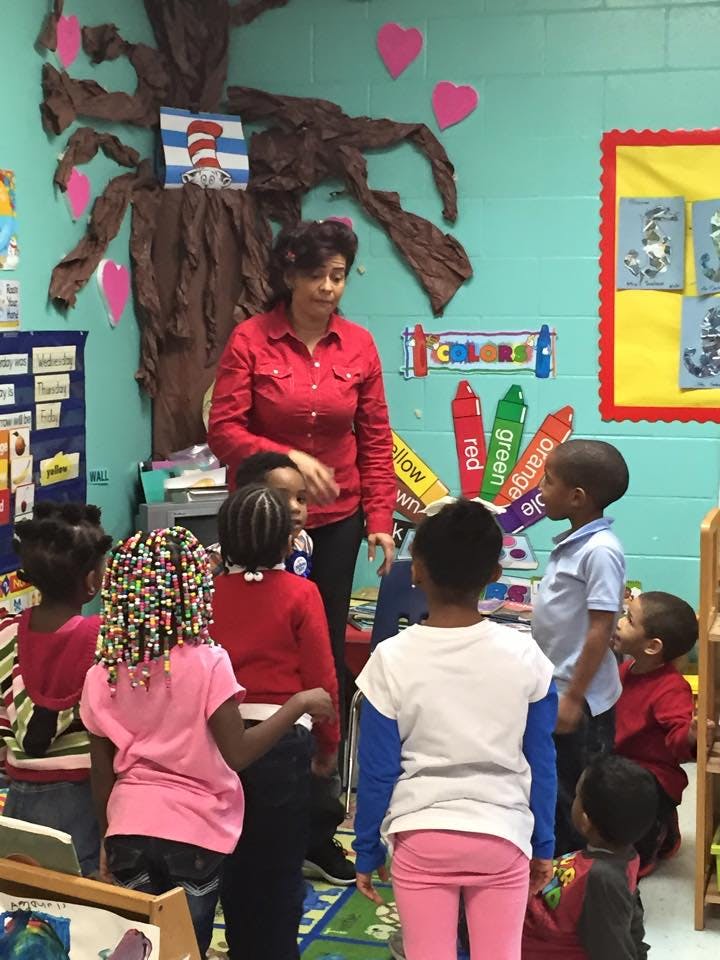Adult person standing with several children in a classroom