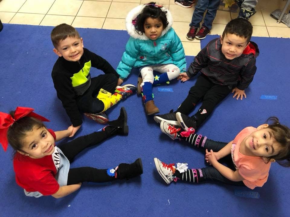 Five children sitting on a blue mat