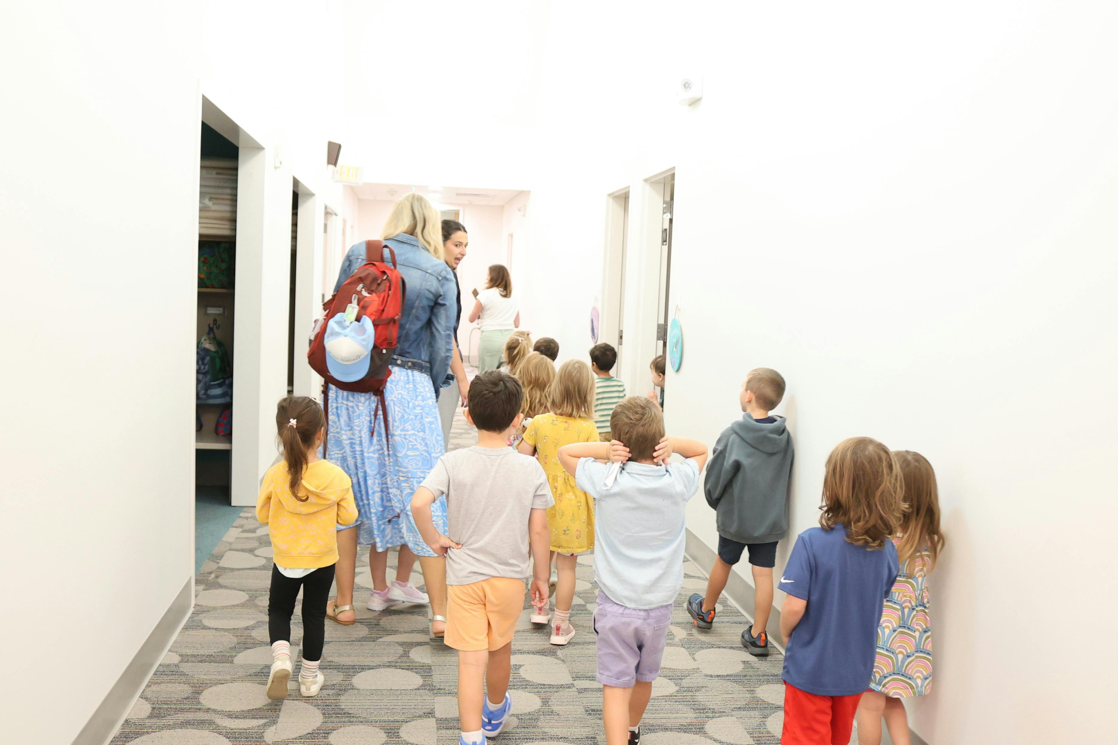 Group of children walking in a school hallway with two adults