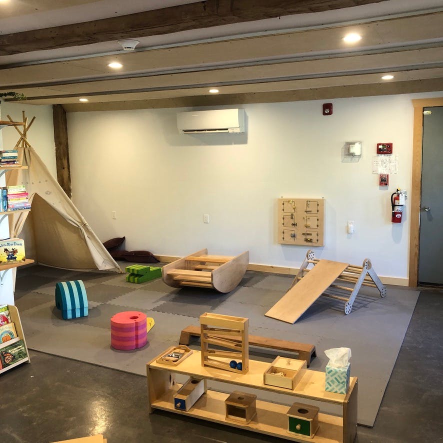 Indoor play area with a teepee, wooden climbing structure, and various toys
