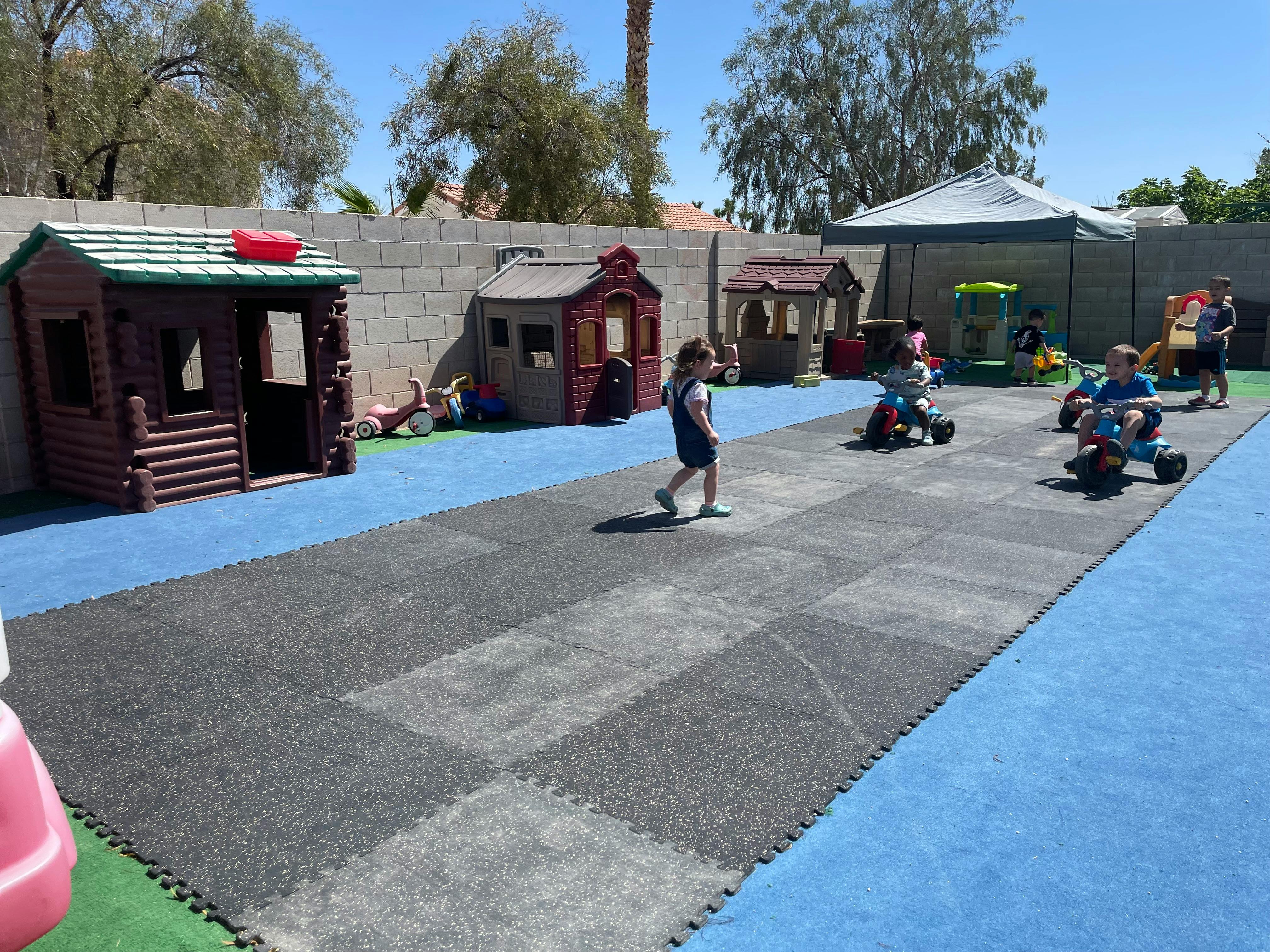Child walking on a playground with playhouses and other children