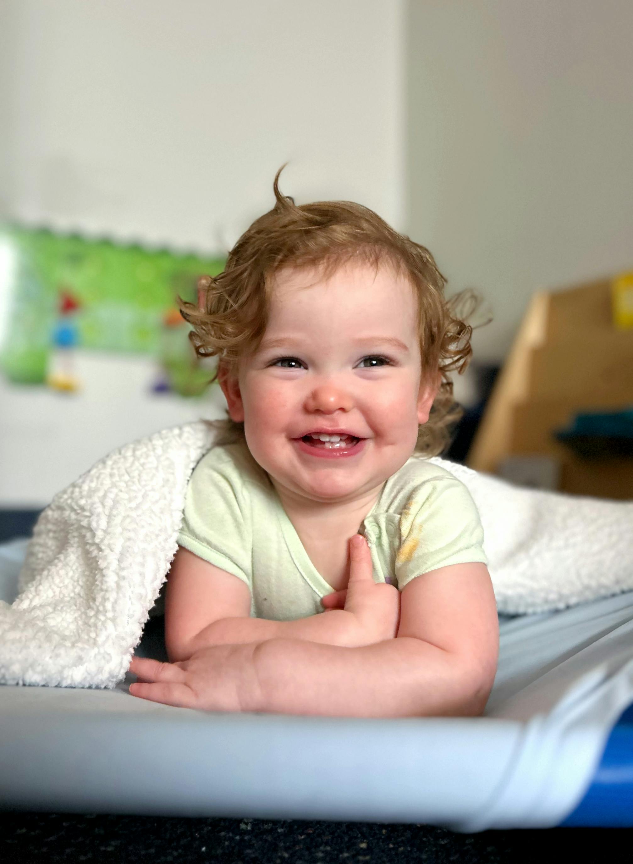 Child smiling while lying on their stomach under a white blanket