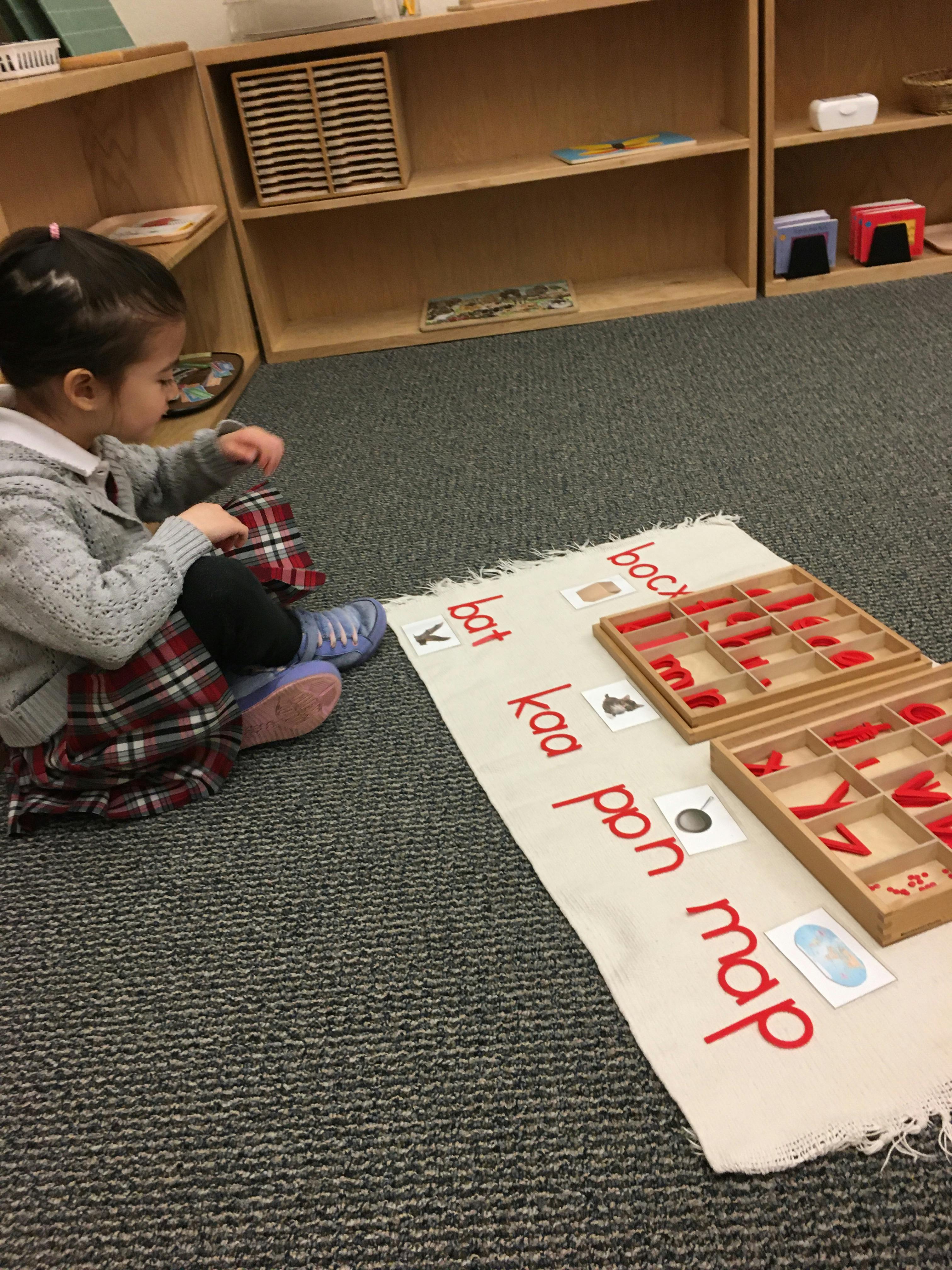 Child sitting on floor with learning materials