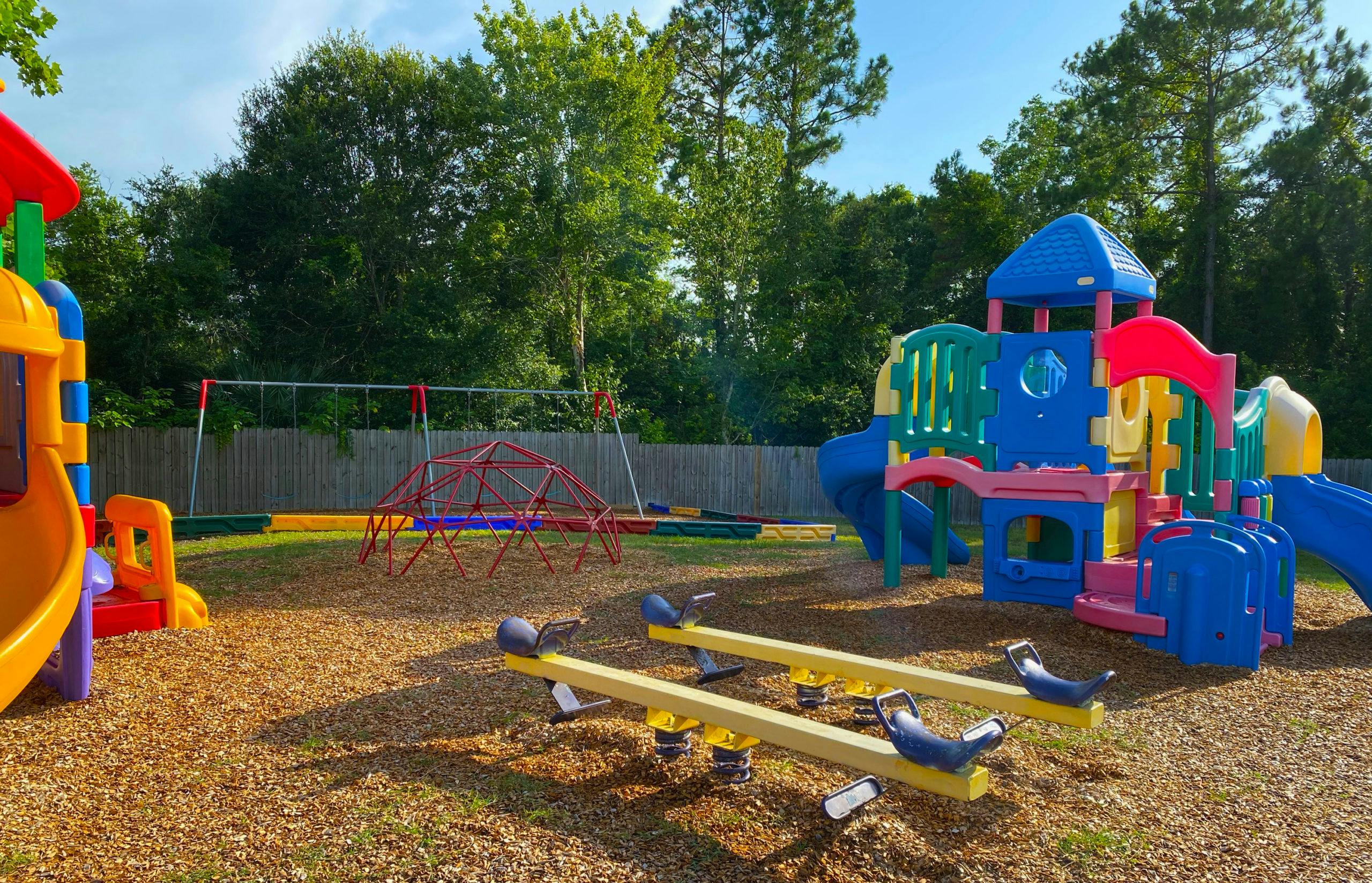 Colorful playground with slides, swings, geodesic dome, and spring riders