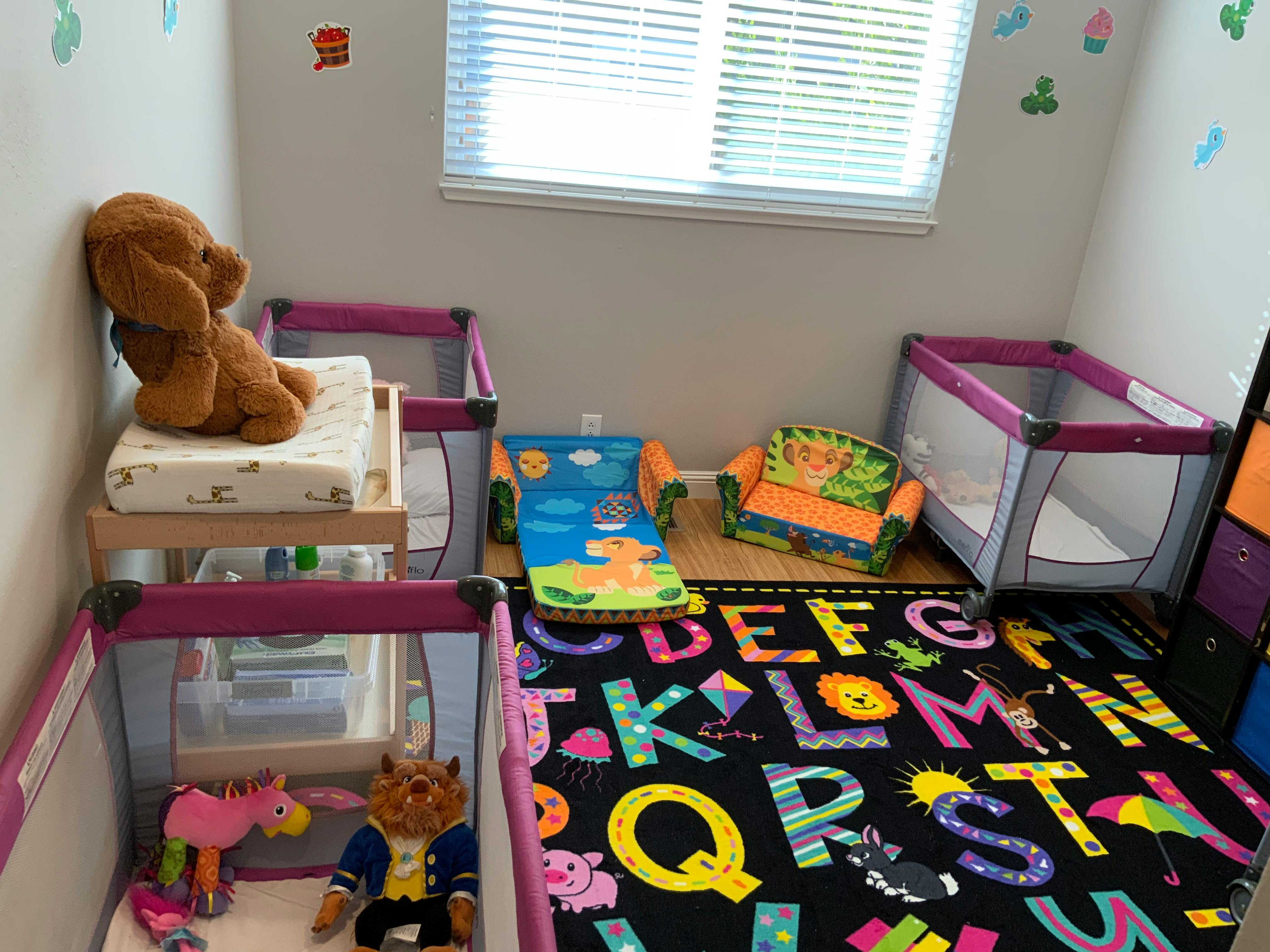 Playroom with two cribs, a changing table, and an alphabet rug