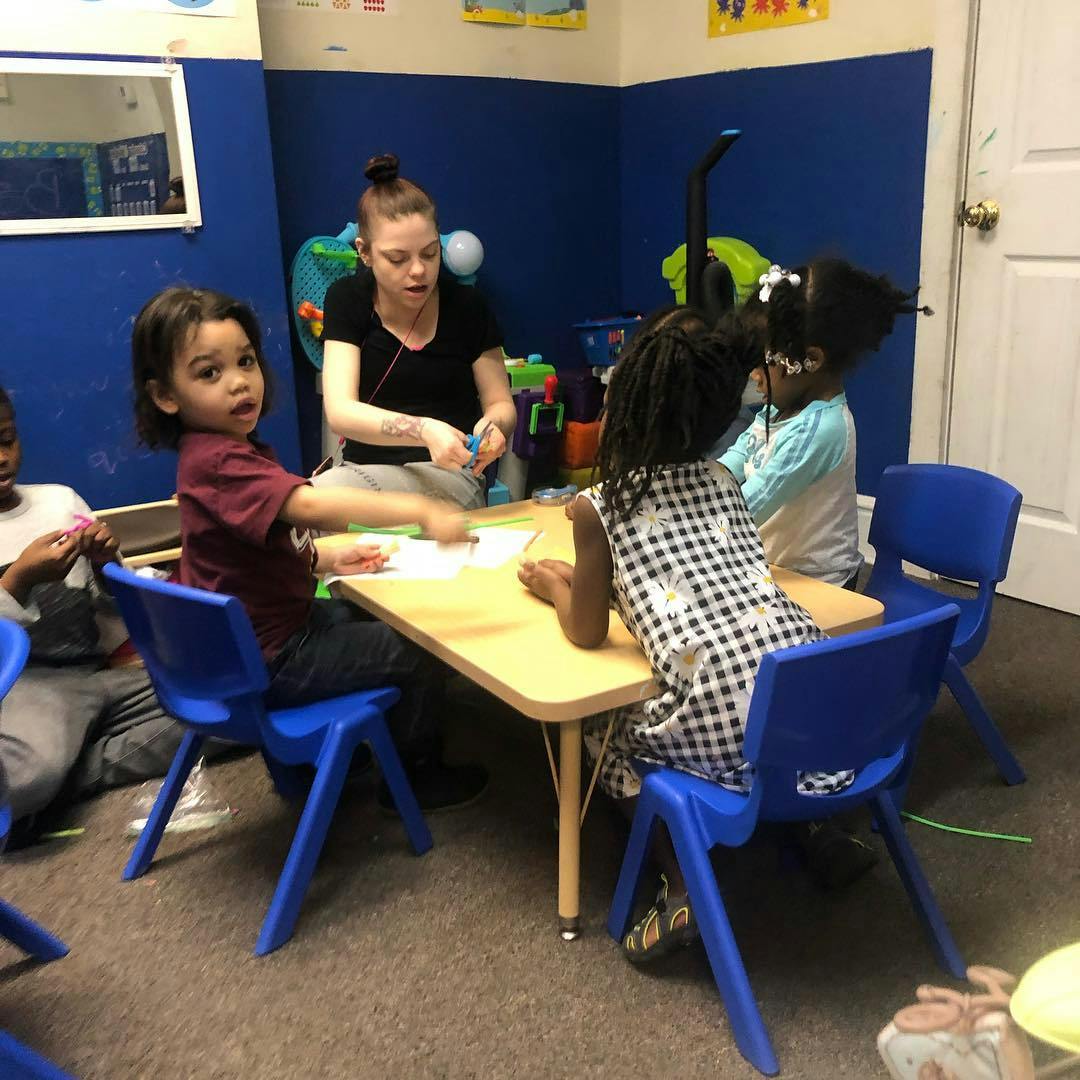 Person and children sitting at a table in a classroom