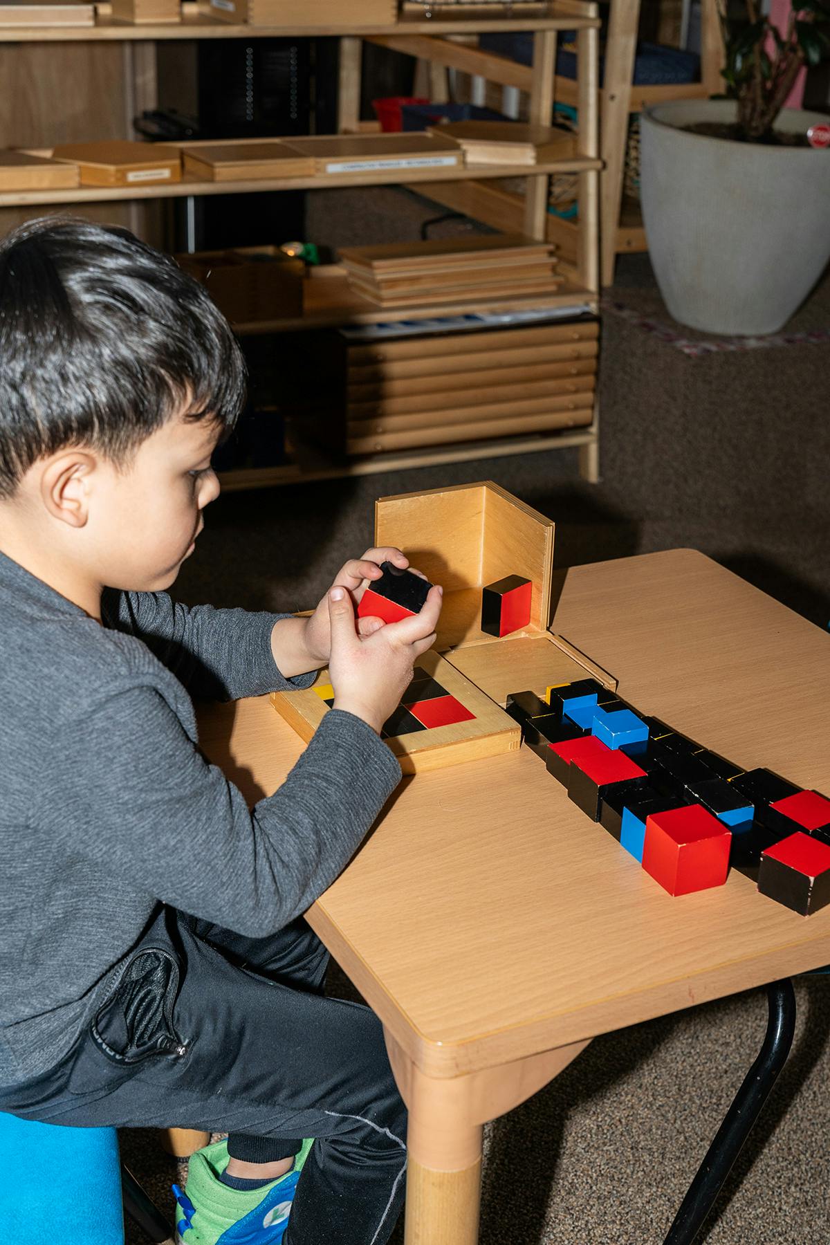 Child playing with red and black blocks at a table