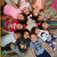 Group of children lying in a circle on the floor looking up