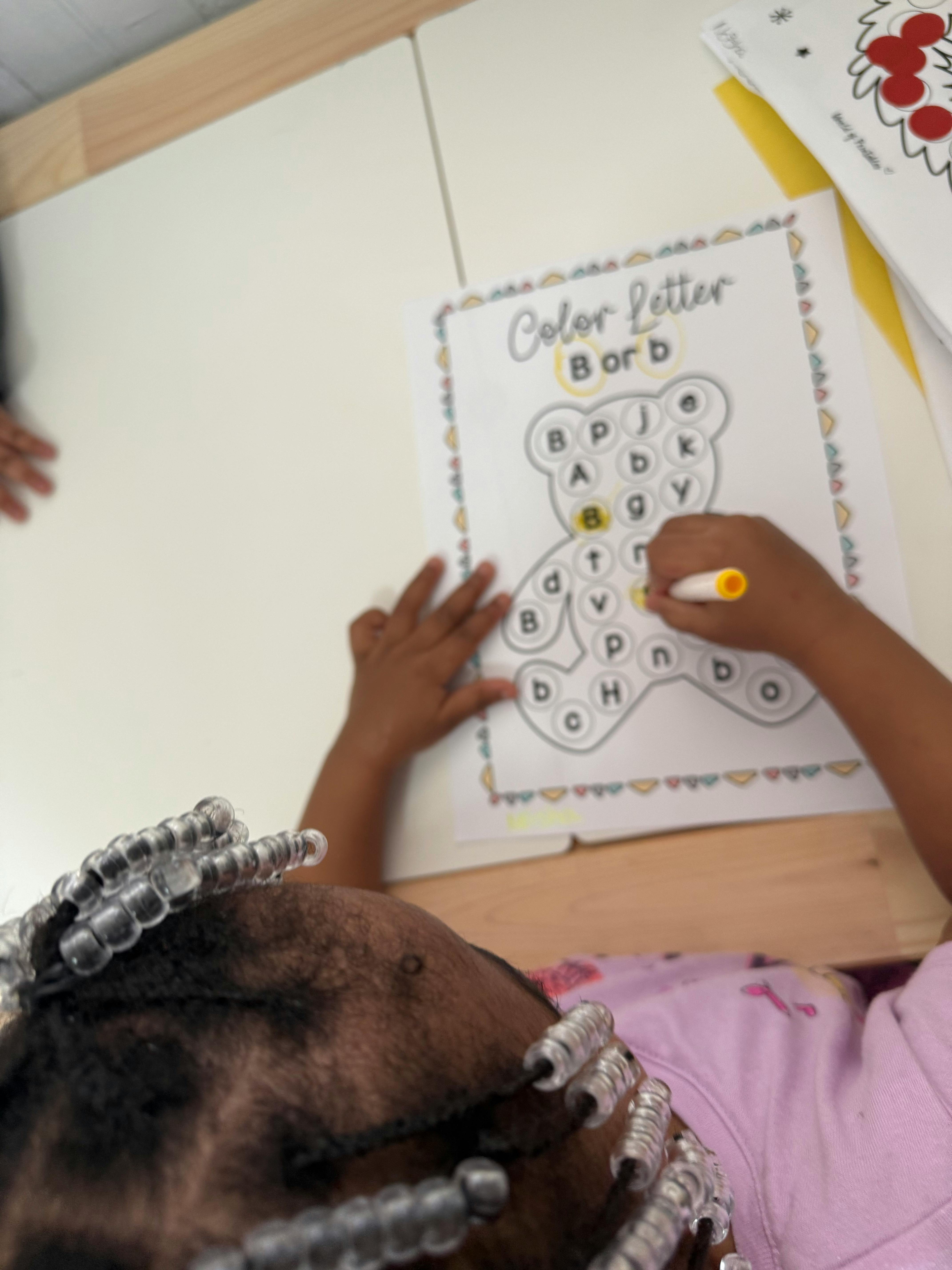 Child coloring letter b on a worksheet
