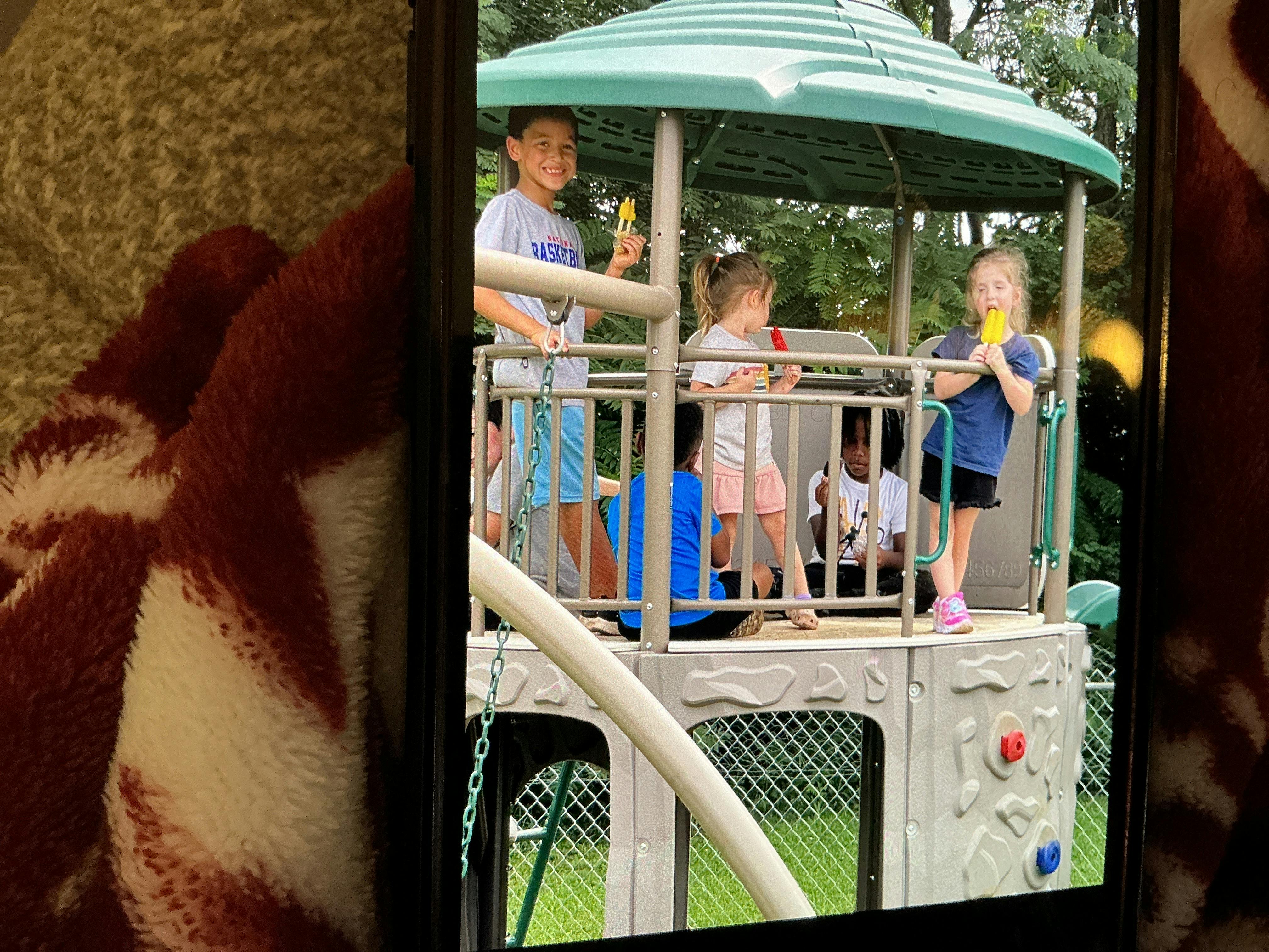 Children eating popsicles on a playground structure