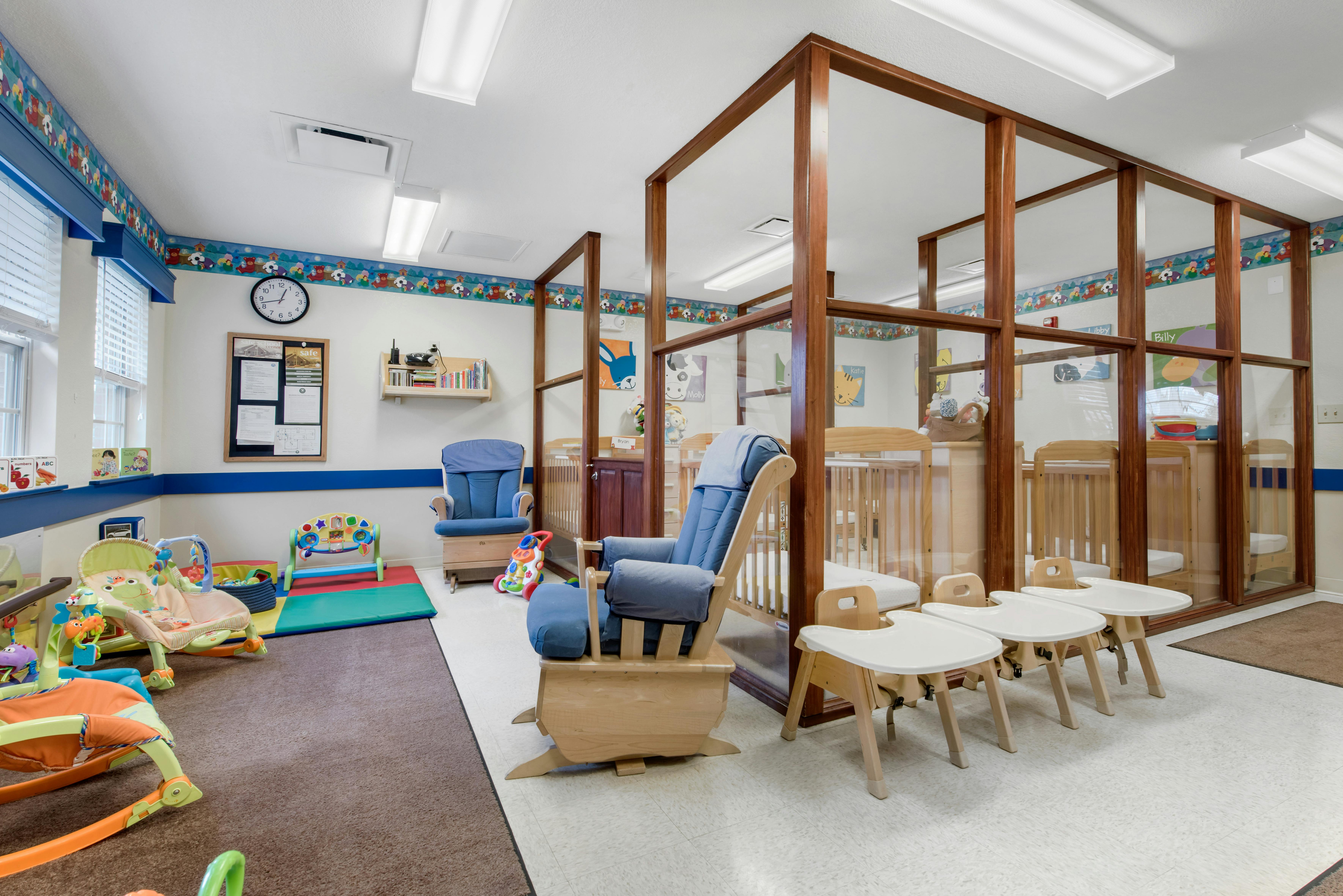 A childcare center with play mats, a changing area, and cribs behind a partition