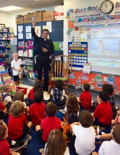 Adult speaking to children seated on floor in classroom